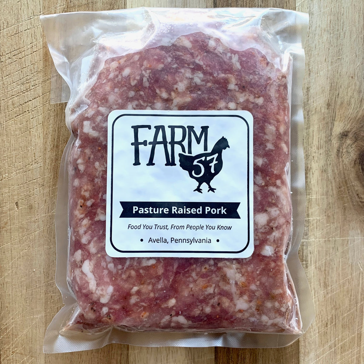 vacuum sealed and frozen pork bulk sausage on wood cutting board with label