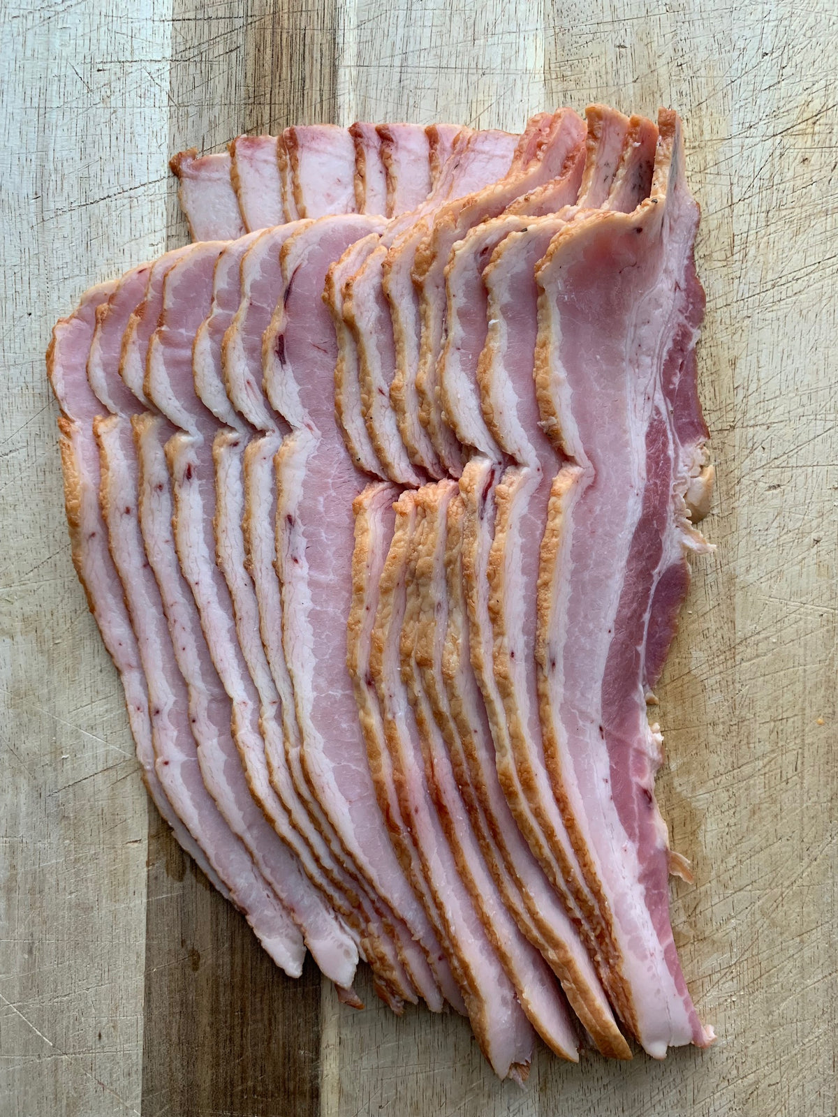raw bacon on a wood cutting board
