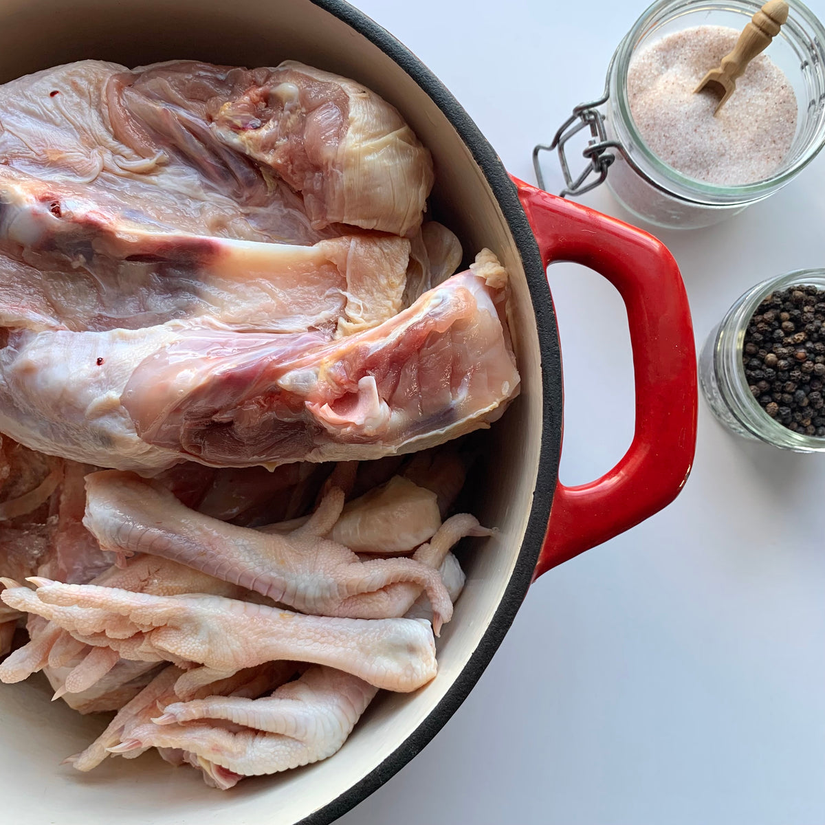 a pot of raw chicken backs and feet alongside salt and peppercorns