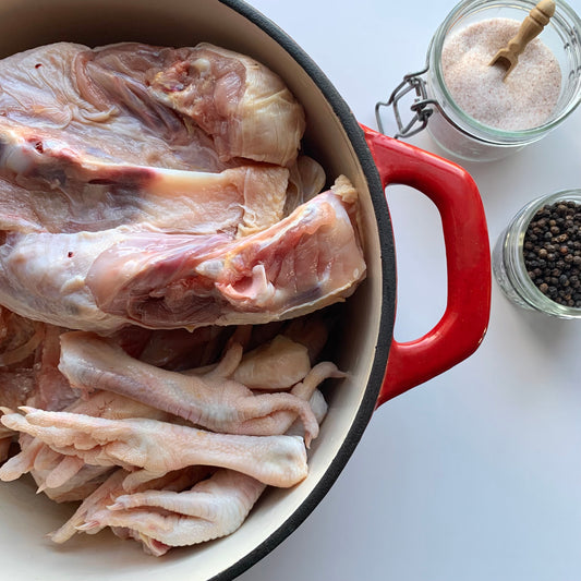 a pot of raw chicken backs and feet alongside salt and peppercorns