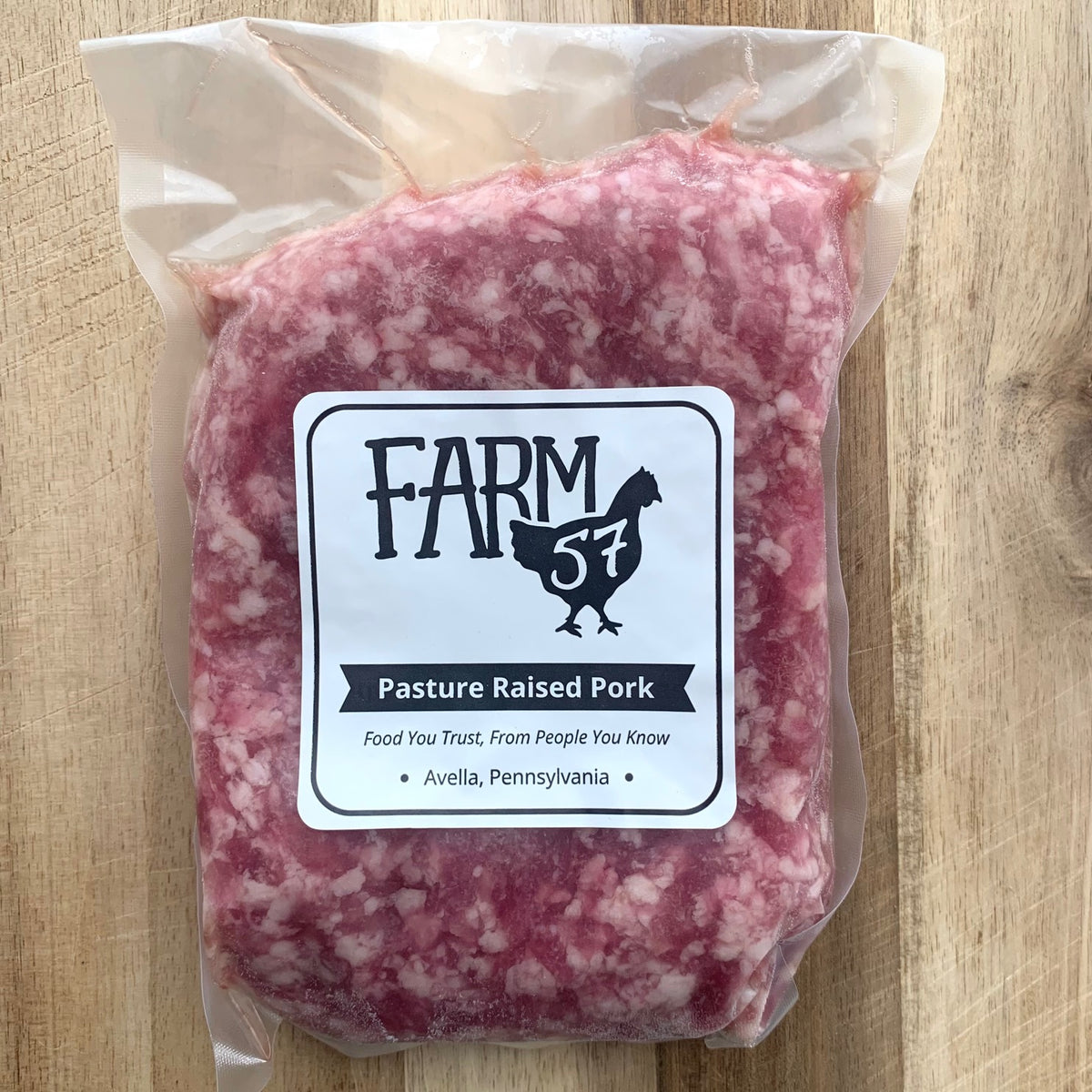 vacuum sealed and frozen ground pork on a wood cutting board with farm57 label 