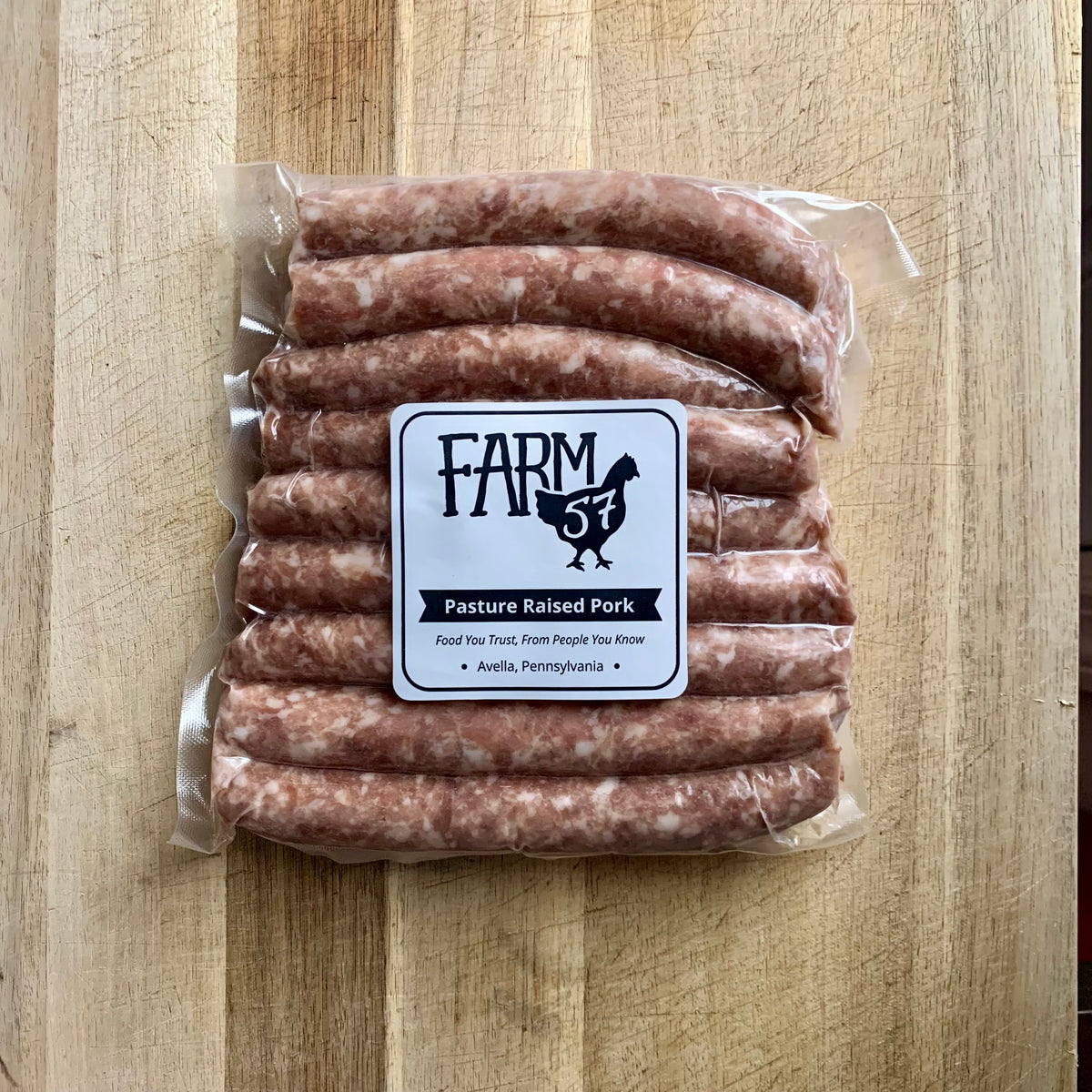 vacuum sealed and frozen maple pork sausage links on wood cutting board with label