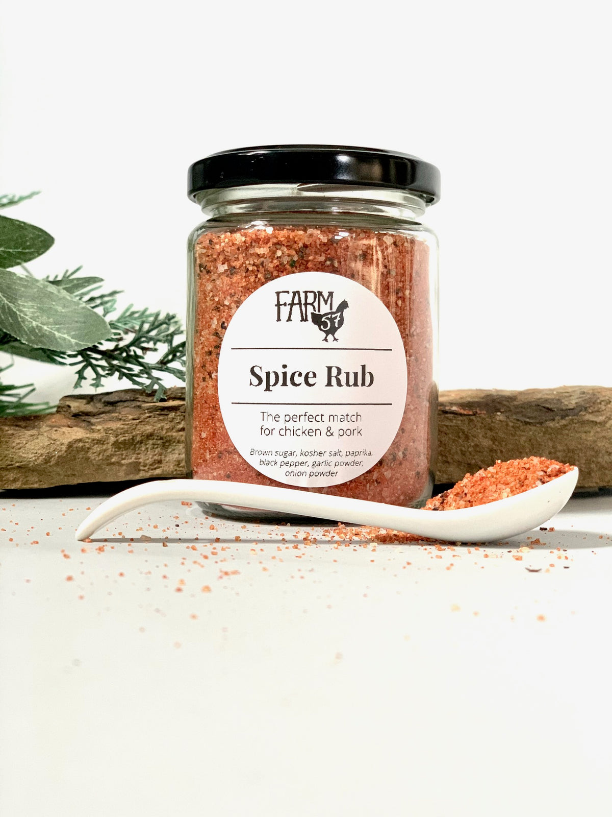 a glass jar of spice blend standing behind a spoonful of loose spice blend