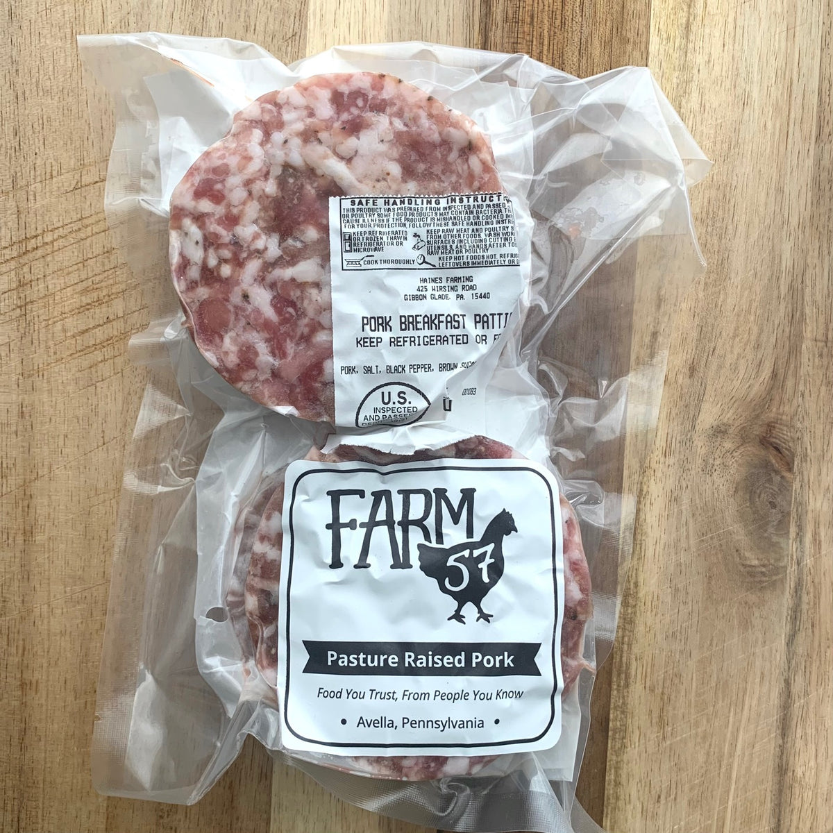 vacuum packaged and frozen breakfast patties on a wooden cutting board with Farm57 label