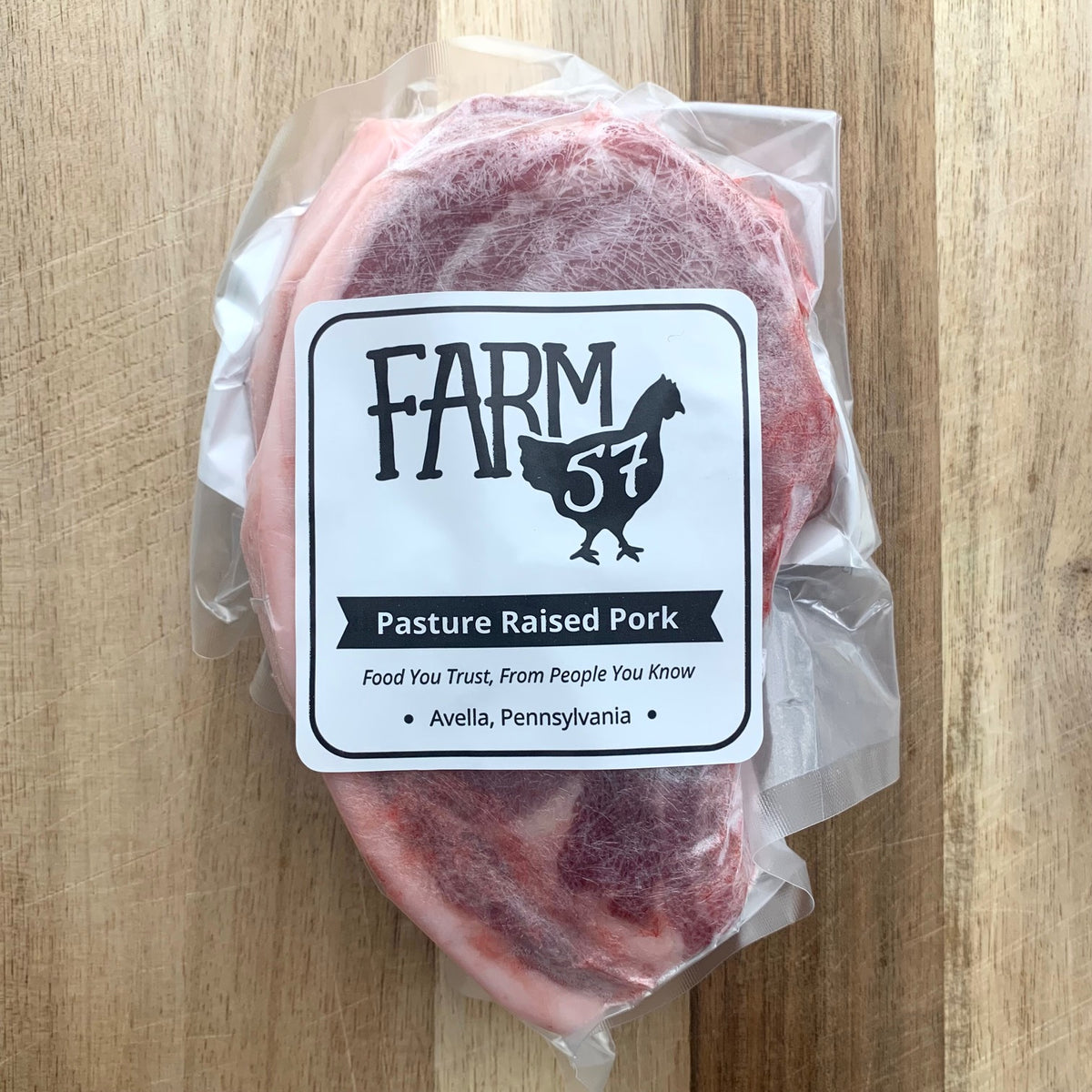 a package of bone-in pork chops on a wood cutting board with a label 