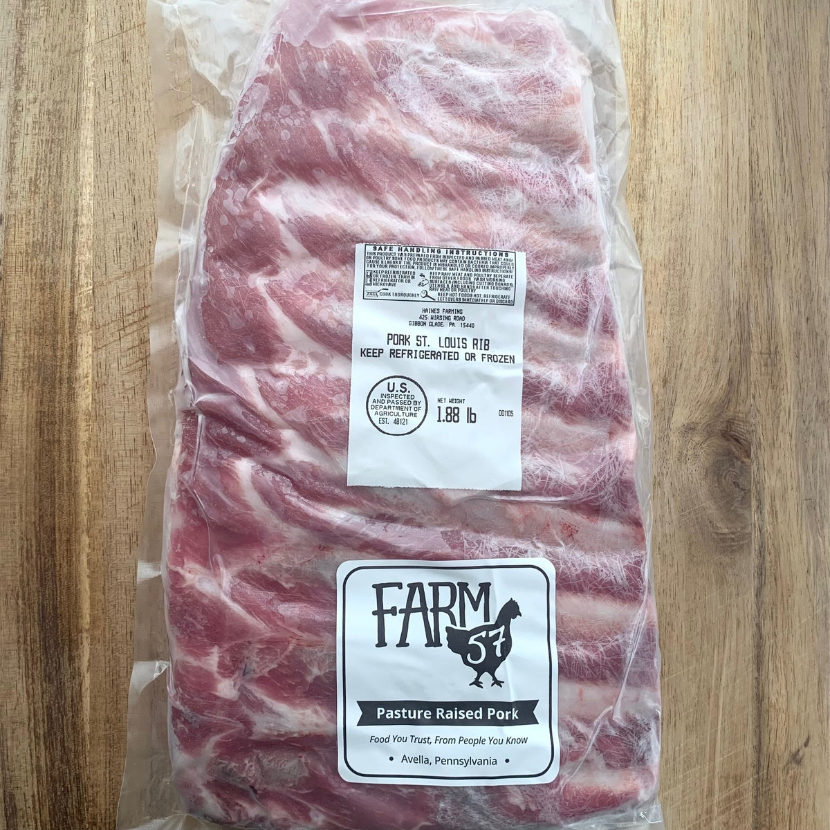 a vacuum sealed and frozen package of ribs on a wood cutting board with farm57 label 