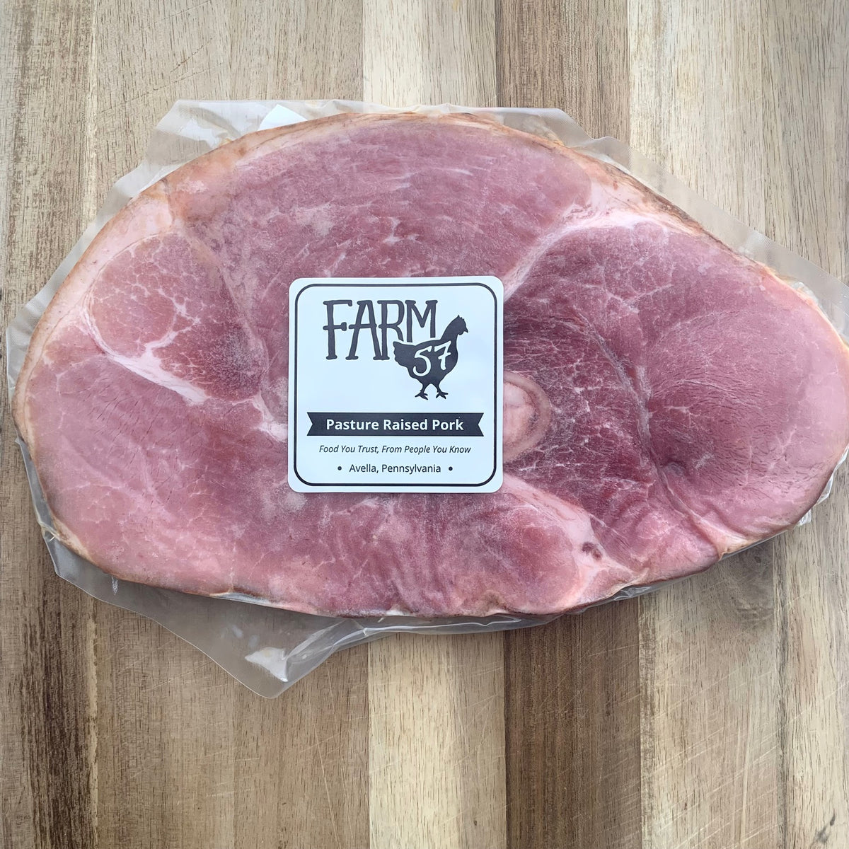 a vacuum sealed and frozen package of one skillet ham slice on a wood cutting board with Farm57 label