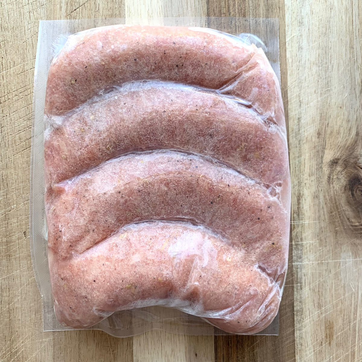 uncooked italian chicken sausages in a package on a wood cutting board