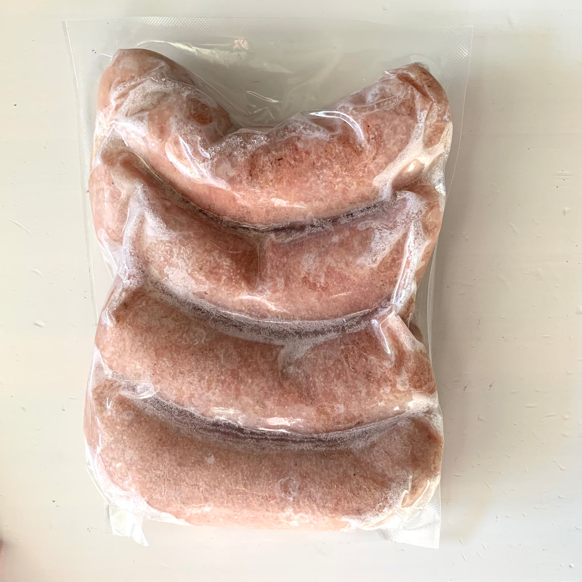 the back of a vacuum sealed and frozen package of chicken sausages